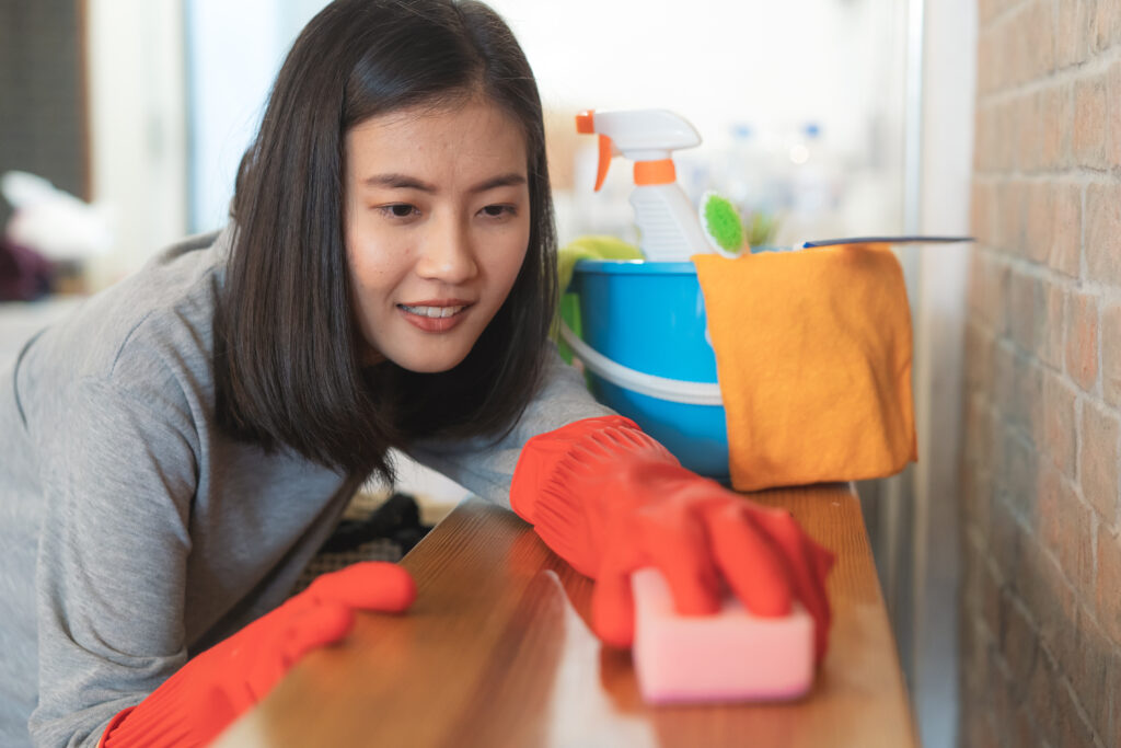Close up woman cleaning kitchen using cleanser spray and cloth.